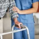 Profesional sanitario junto a una persona que utiliza un andador