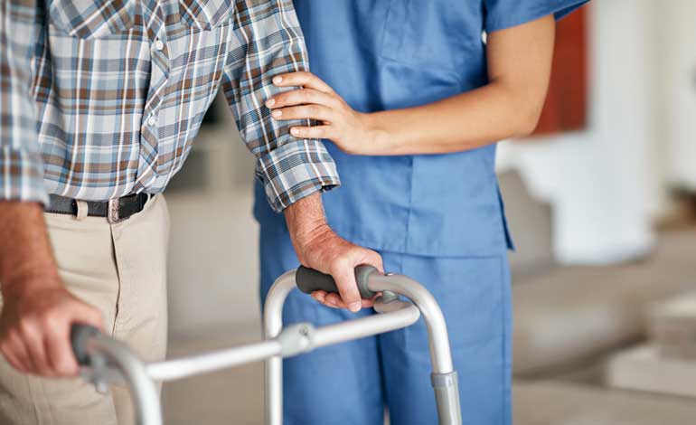Profesional sanitario junto a una persona que utiliza un andador