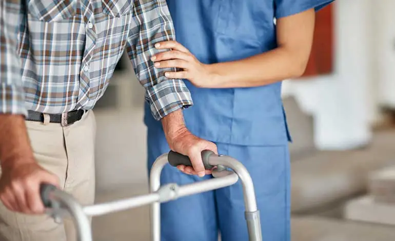 Profesional sanitario junto a una persona que utiliza un andador